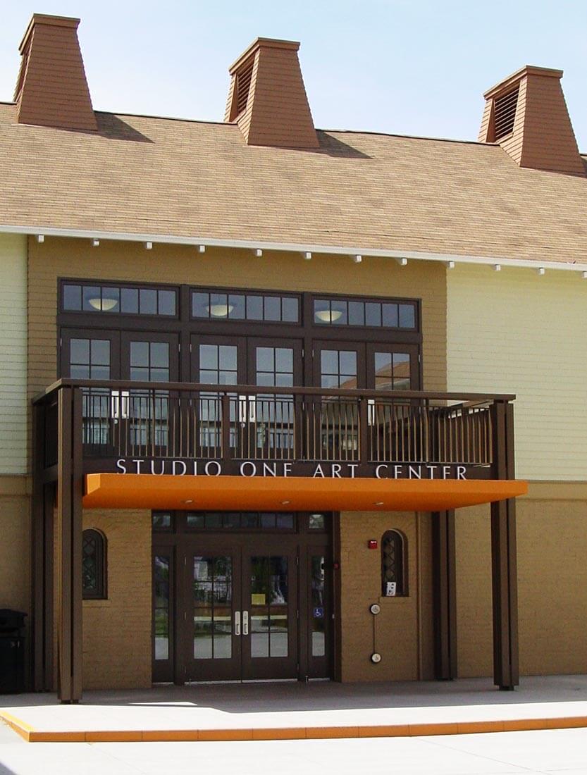 Exterior view of historical brick and wood structure with 'Studio One Arts Center' signage above front entry door